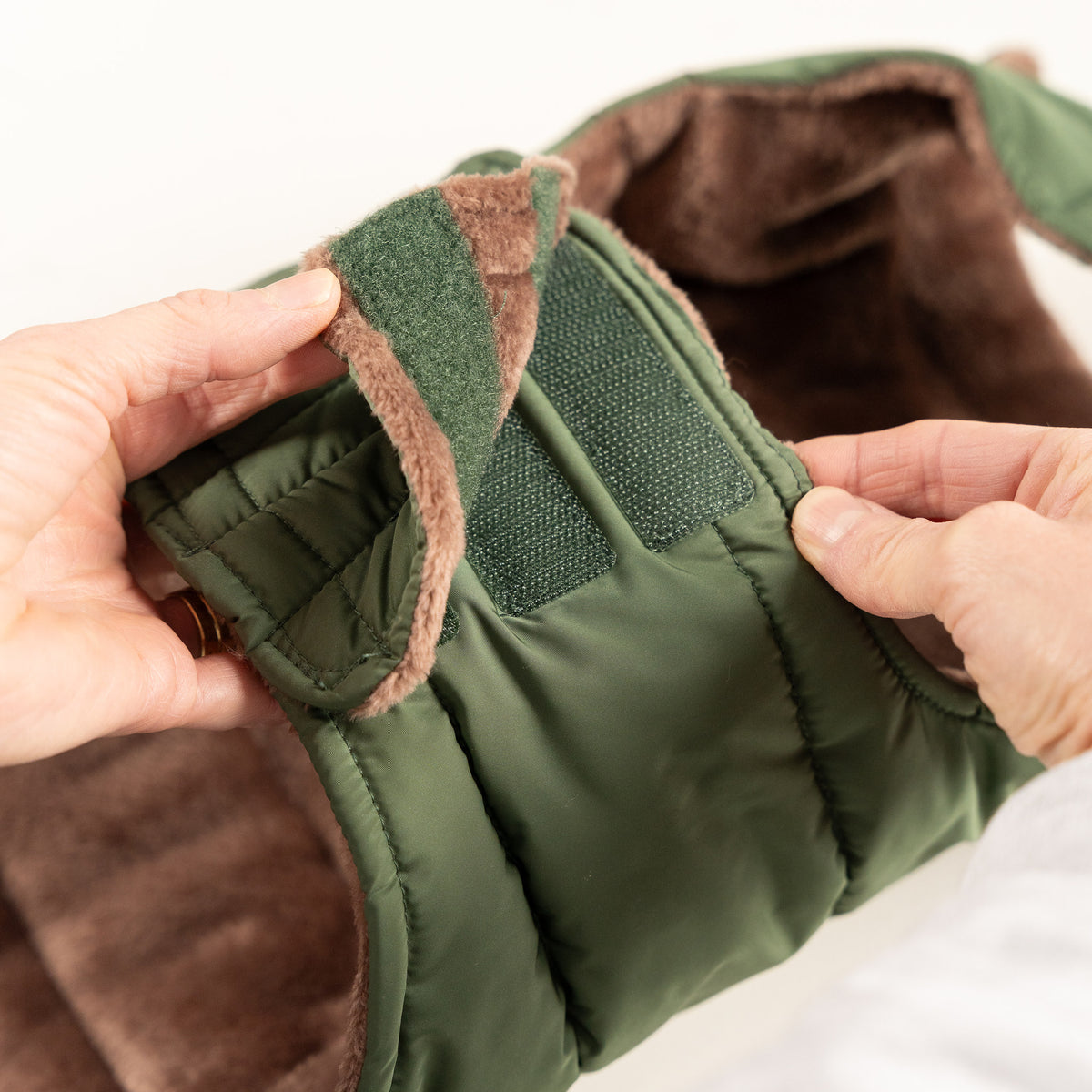 Close-up of the secure hook-and-loop chest fastening on the Woodland Green dog puffer coat